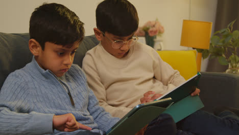 Two-Young-Boys-Sitting-On-Sofa-At-Home-Playing-Games-Or-Streaming-Onto-Digital-Tablets-6